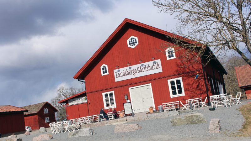 Frontfasad på Landsberga gård med uteservering och stenparti.
