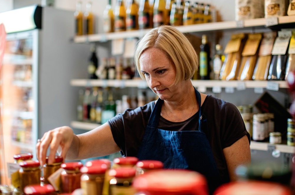 Butiks-expedit som sorterar varor i en hylla.